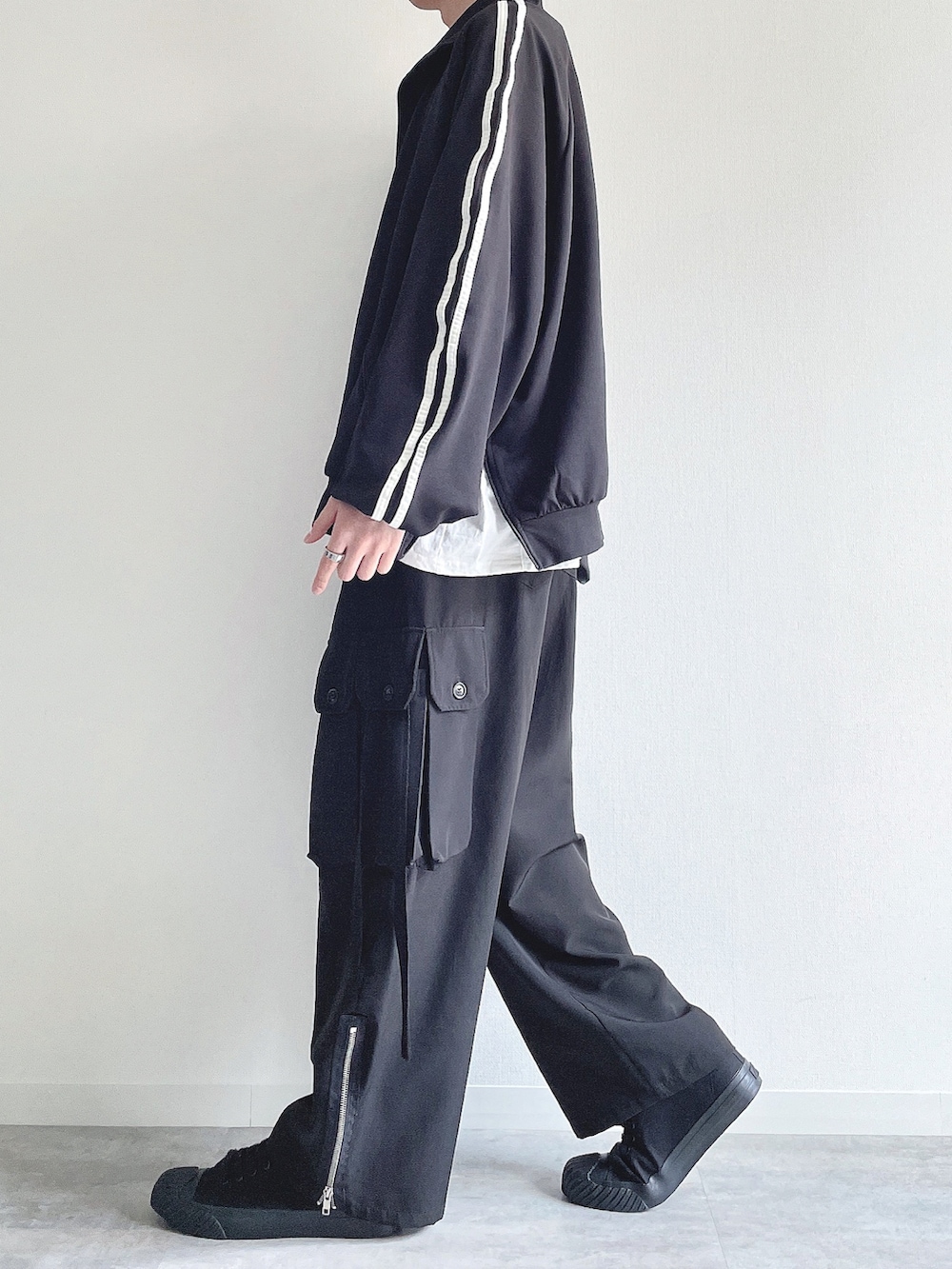 ブラック系のブルゾン、ホワイト系のTシャツ/カットソー、ブラック系のカーゴパンツを着用したメンズの春コーディネートの3枚目の写真