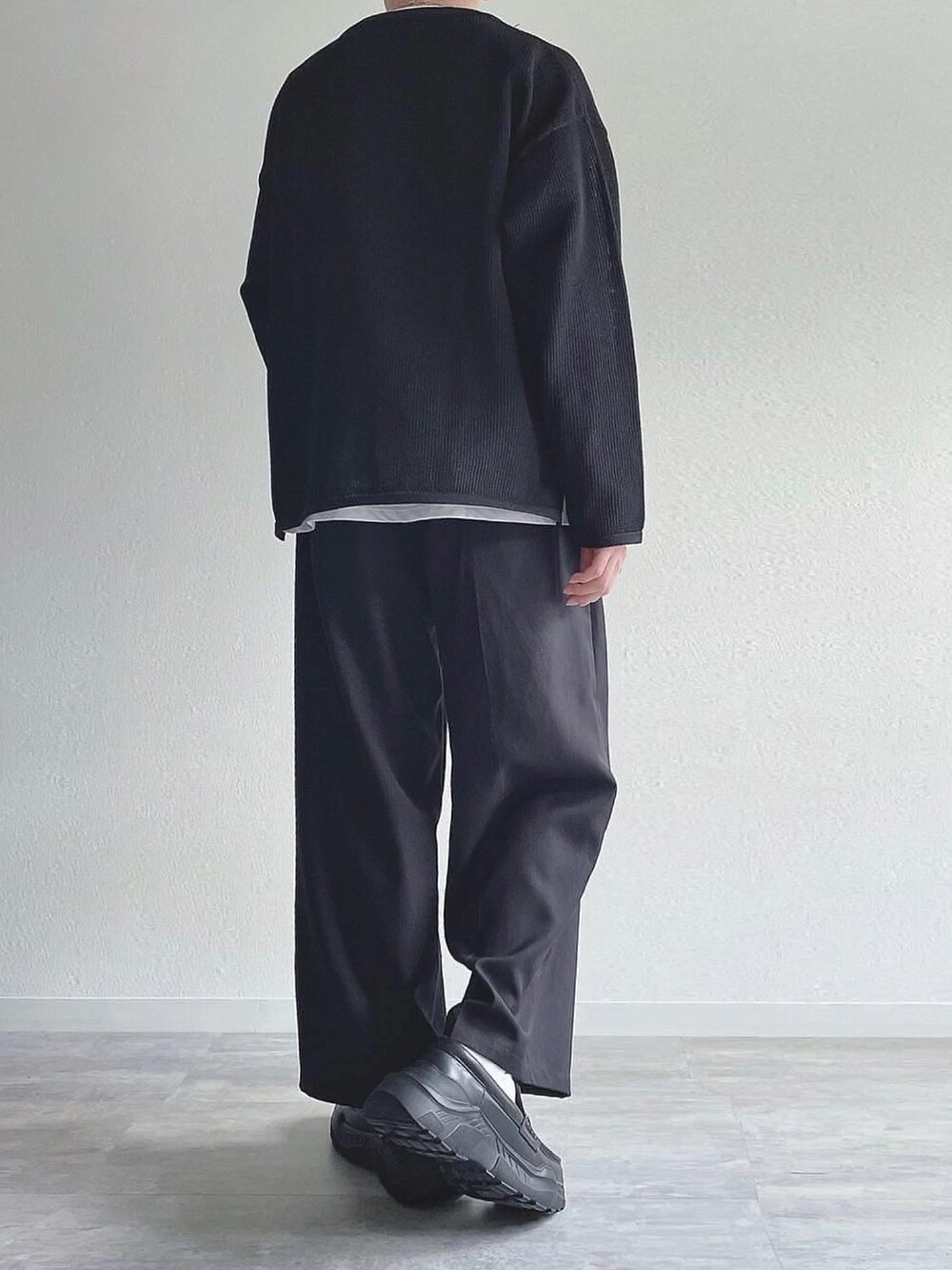 ブラック系のトップス、ブラック系のスラックス、ブラック系のスニーカーを着用したメンズの秋コーディネートの4枚目の写真