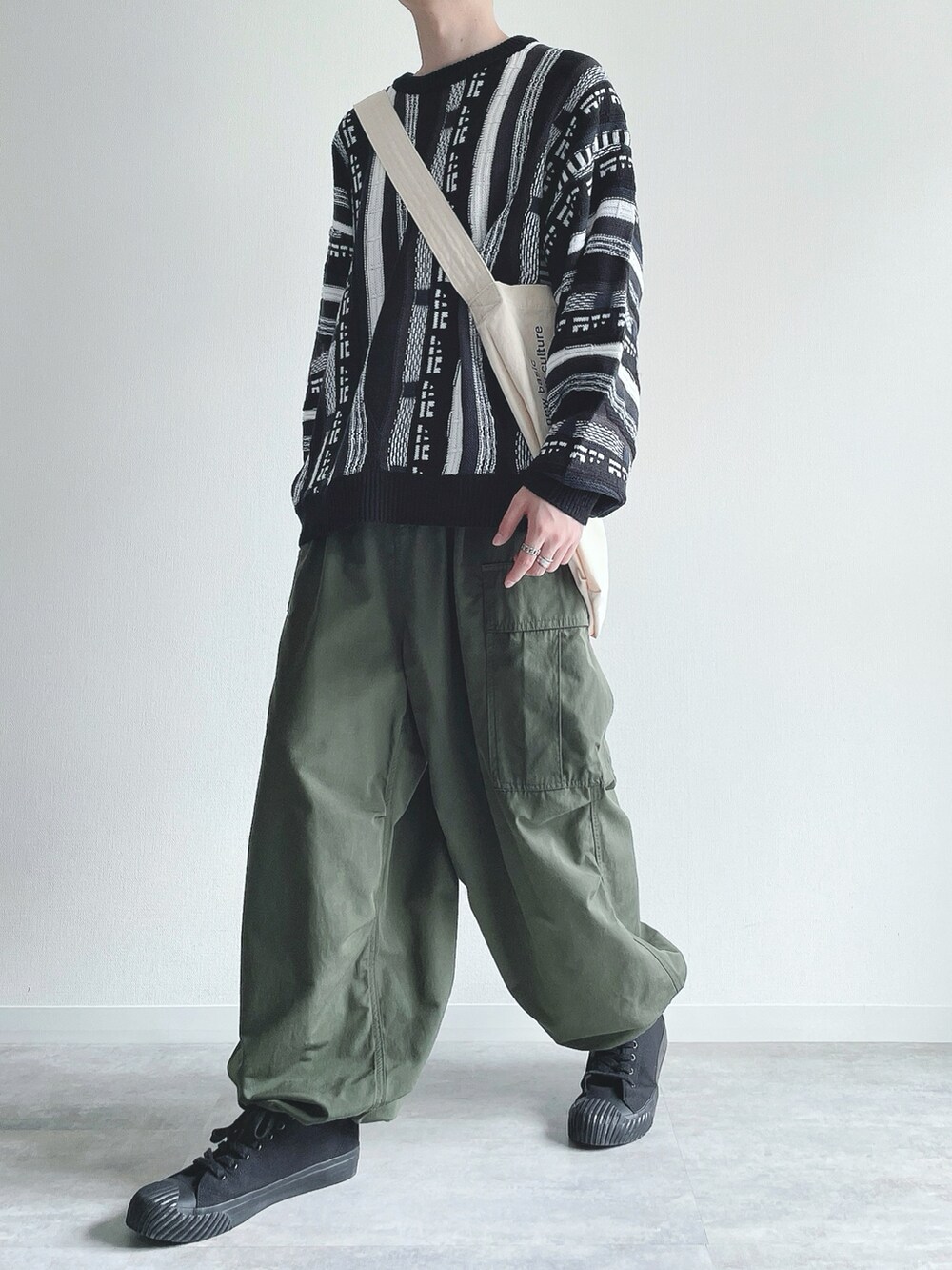 ブラック系のニット/セーター、グリーン系のカーゴパンツ、ブラック系のスニーカーを着用したメンズの冬コーディネートの5枚目の写真