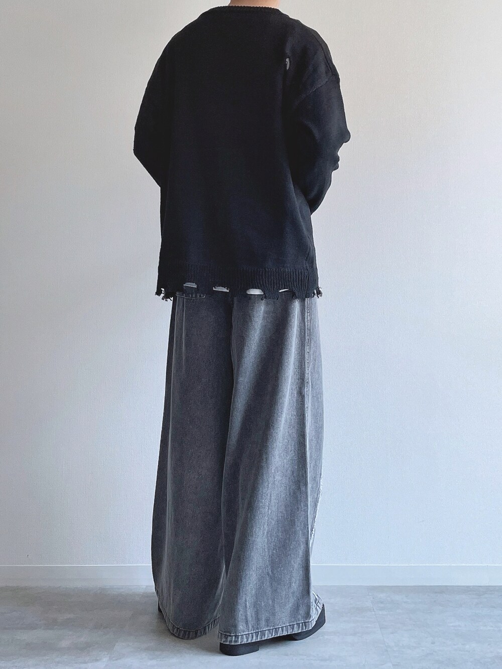 ブラック系のニット/セーター、ホワイト系のTシャツ/カットソー、グレー系のデニムパンツを着用したメンズの冬コーディネートの4枚目の写真