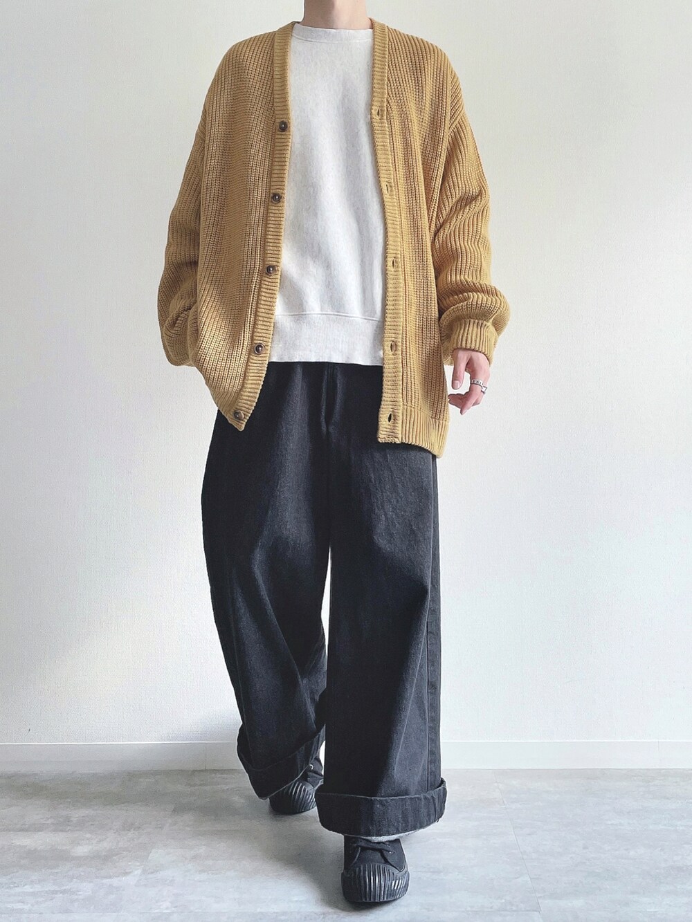 イエロー系のカーディガン/ボレロ、グレー系のトップス、ブラック系のデニムパンツを着用したメンズの秋コーディネートの2枚目の写真