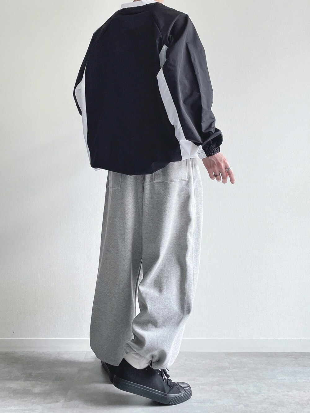 ブラック系のパーカー、グレー系のパンツ、ブラック系のスニーカーを着用したメンズの春コーディネートの4枚目の写真