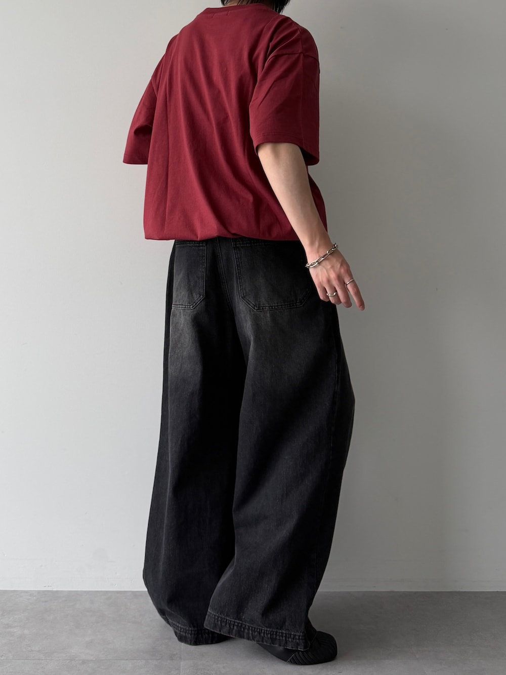 レッド系のTシャツ/カットソー、ブラック系のスニーカー、ブラック系のデニムパンツを着用したメンズの夏コーディネートの3枚目の写真
