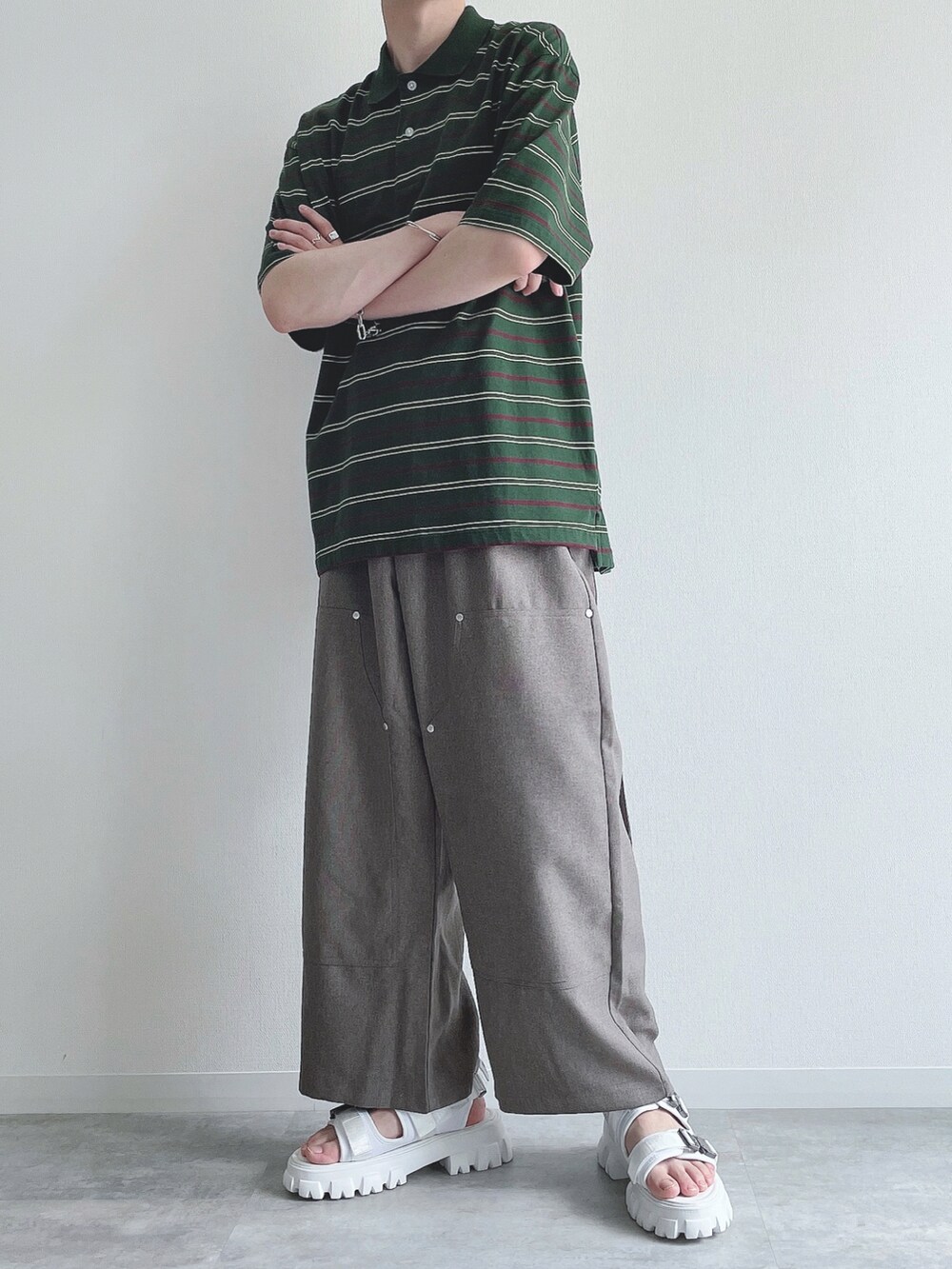 グリーン系のトップス、ベージュ系のスラックス、ホワイト系のサンダルを着用したメンズの夏コーディネートの5枚目の写真