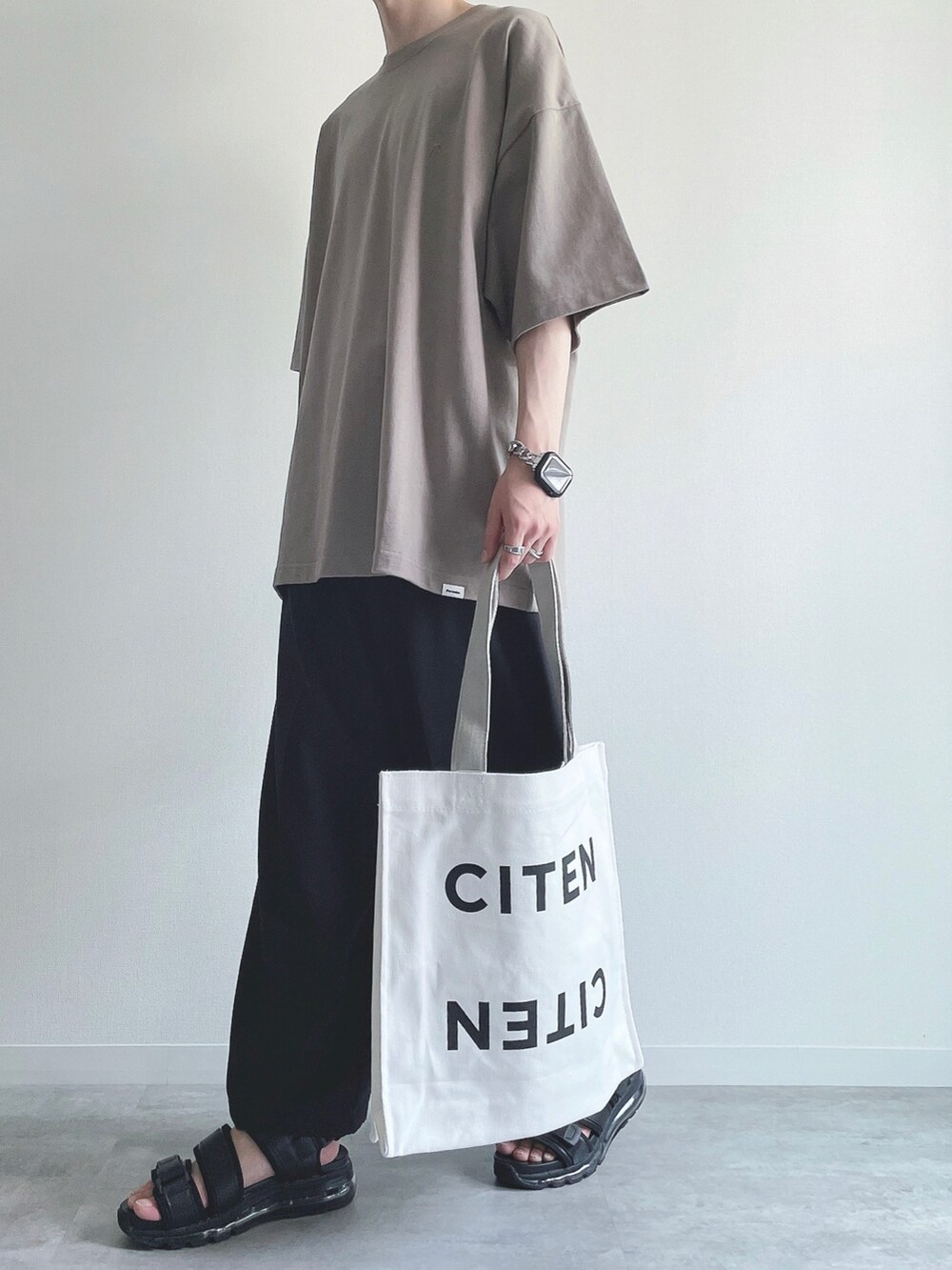 ベージュ系のTシャツ/カットソー、ブラック系のスラックス、ブラック系のサンダルを着用したメンズの夏コーディネートの5枚目の写真