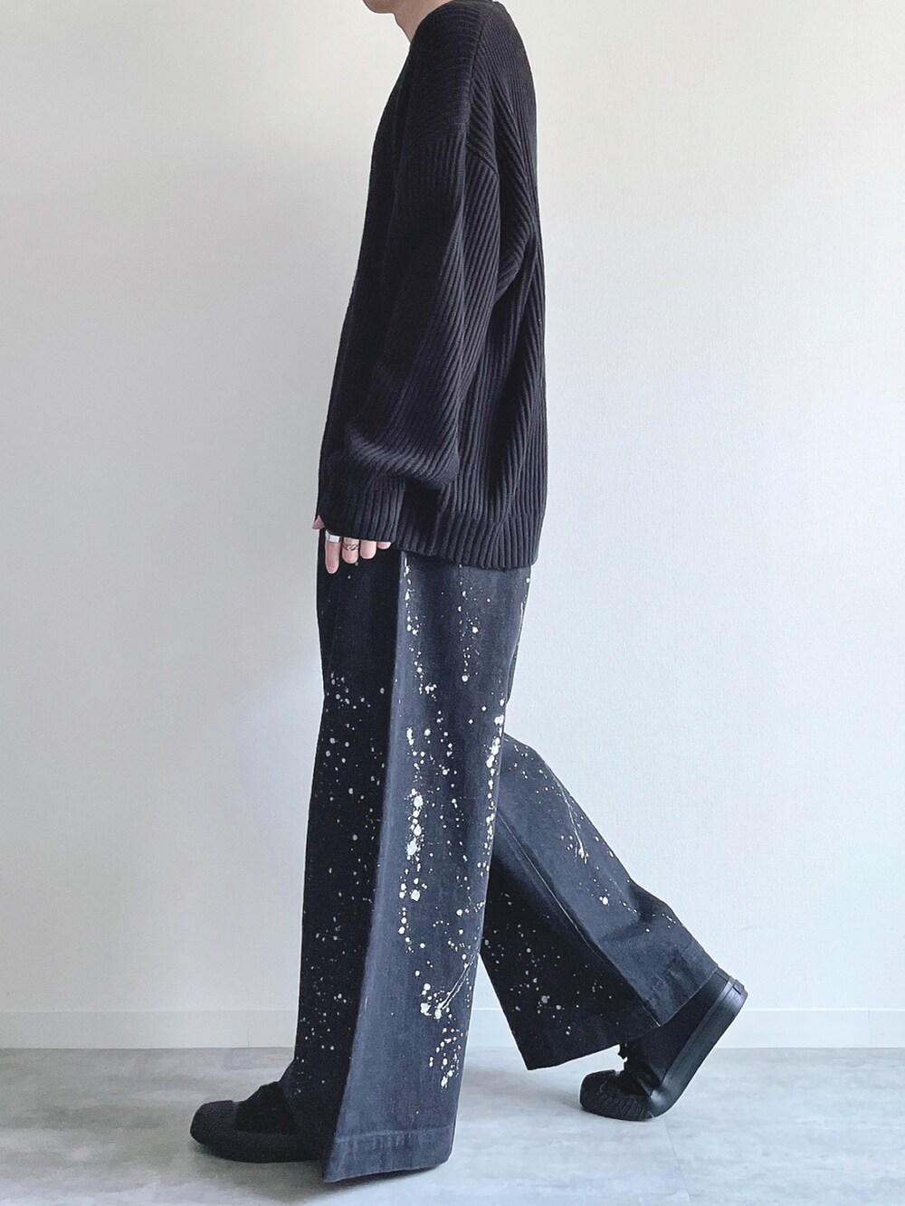 ブラック系のニット/セーター、ブラック系のデニムパンツ、ブラック系のスニーカーを着用したメンズの春コーディネートの3枚目の写真