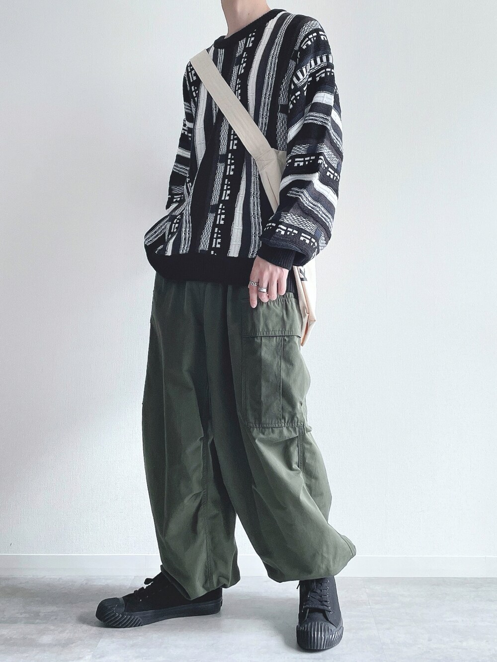 ブラック系のニット/セーター、グリーン系のカーゴパンツ、ブラック系のスニーカーを着用したメンズの冬コーディネートの3枚目の写真