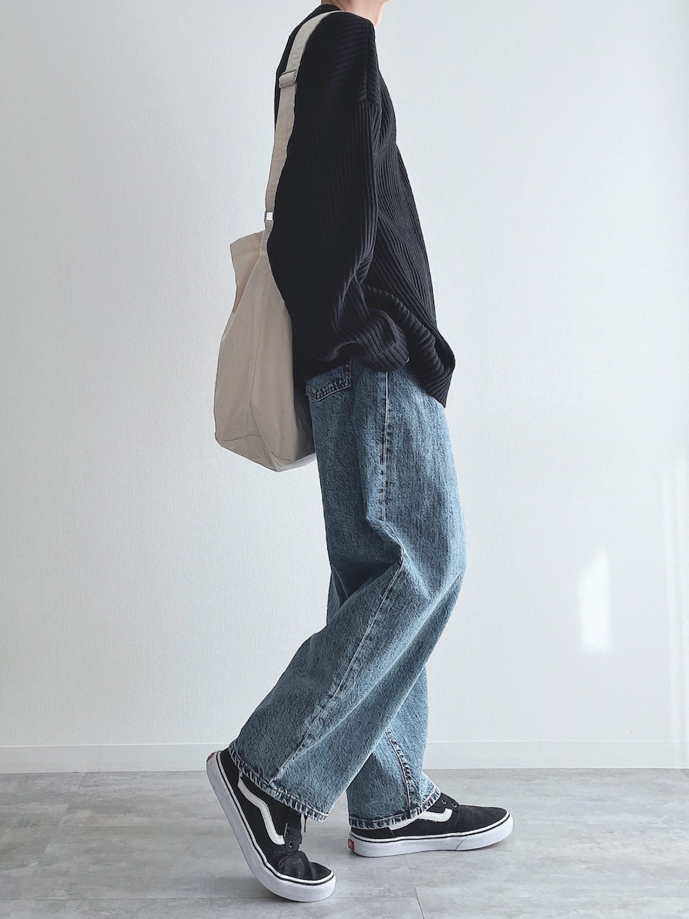 ブラック系のニット/セーター、ブルー系のパンツ、ブラック系のスニーカーを着用したメンズの冬コーディネートの2枚目の写真