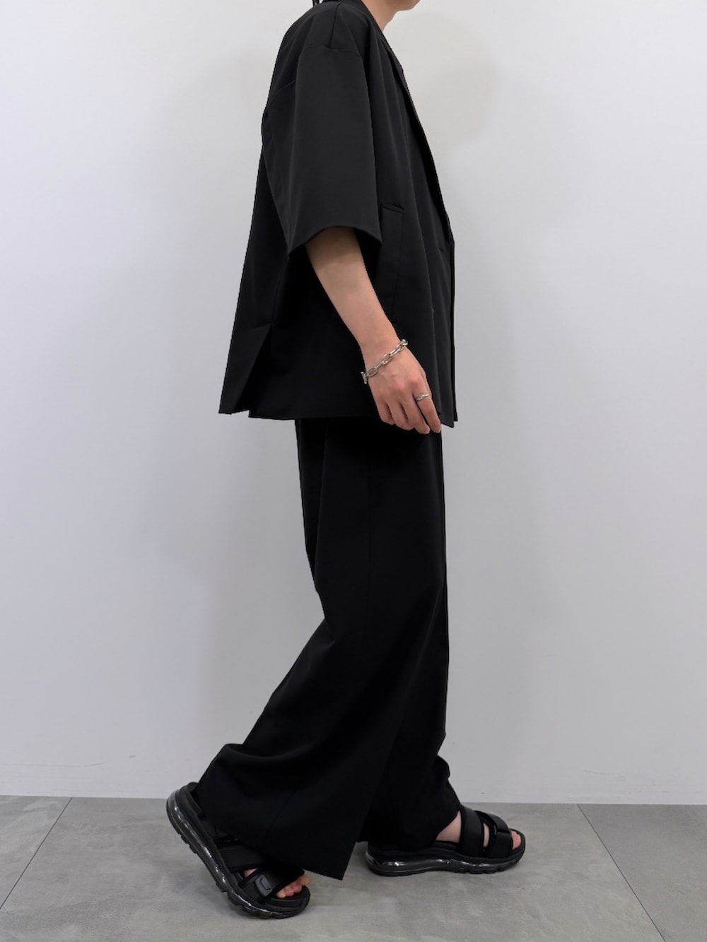 ホワイト系のTシャツ/カットソー、ブラック系のセットアップ、ブラック系のサンダルを着用したメンズの春コーディネートの3枚目の写真
