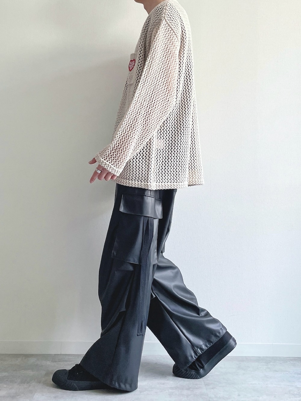 ホワイト系のニット/セーター、ブラック系のTシャツ/カットソー、ブラック系のカーゴパンツを着用したメンズの春コーディネートの3枚目の写真