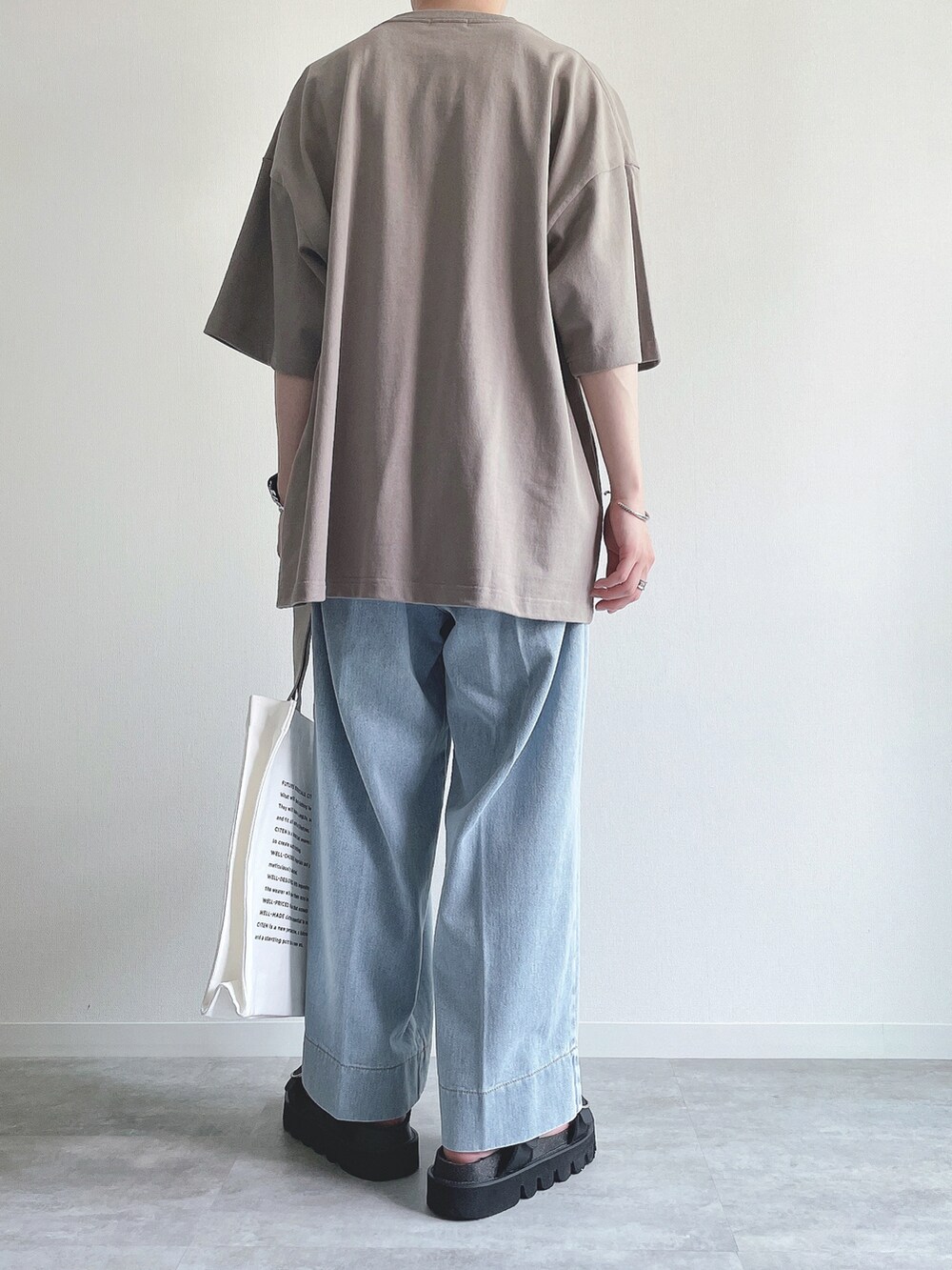ベージュ系のTシャツ/カットソー、ブルー系のデニムパンツ、ブラック系のサンダルを着用したメンズの夏コーディネートの4枚目の写真