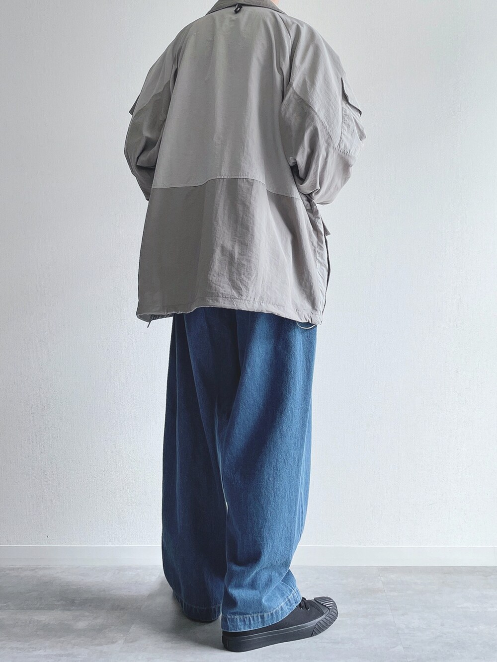 グレー系のブルゾン、ホワイト系のトップス、ブルー系のデニムパンツを着用したメンズの冬コーディネートの3枚目の写真