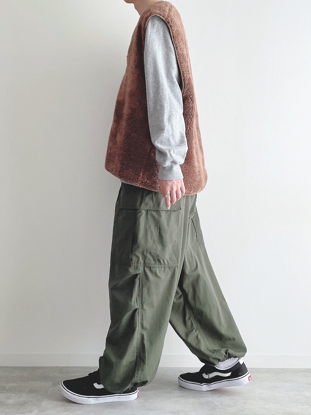 ブラウン系のベスト、グレー系のトップス、グリーン系のカーゴパンツを着用したメンズの秋コーディネートの3枚目の写真