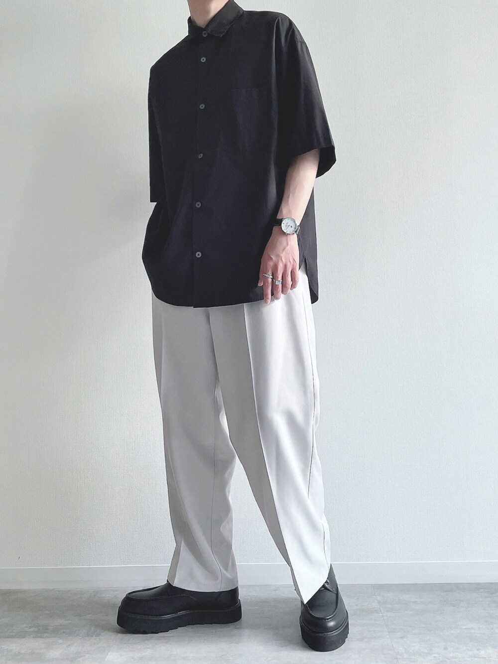 ブラック系のトップス、ホワイト系のスラックス、ブラック系のモカシン/デッキシューズを着用したメンズの夏コーディネートの5枚目の写真