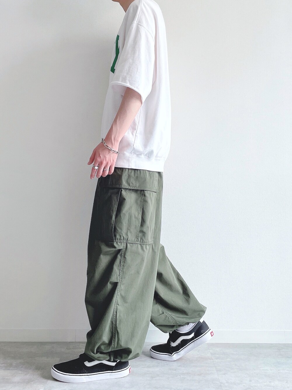 ホワイト系のTシャツ/カットソー、グリーン系のカーゴパンツ、ブラック系のスニーカーを着用したメンズの夏コーディネートの3枚目の写真