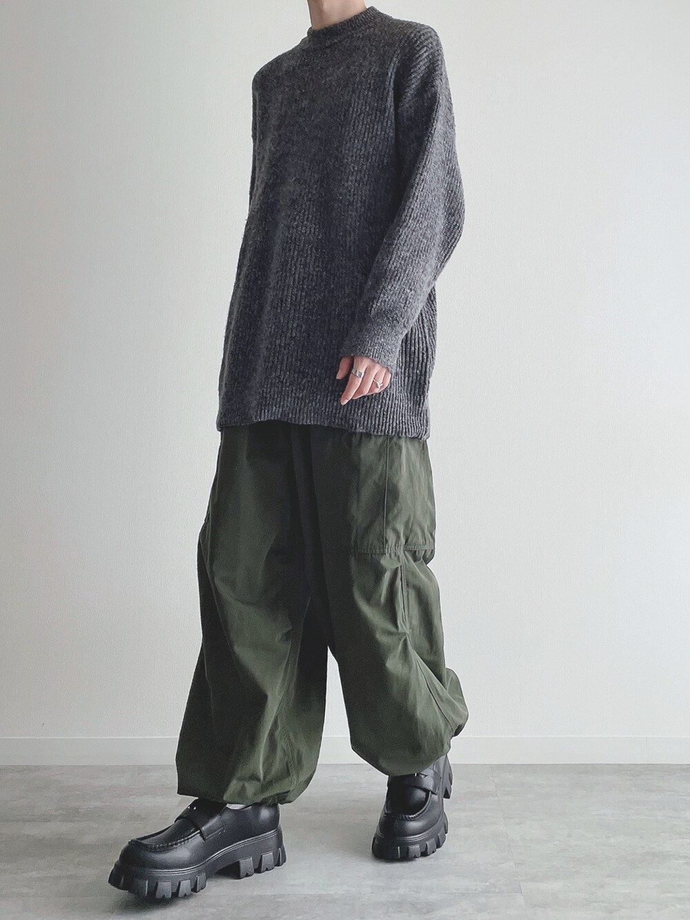 グレー系のニット/セーター、グリーン系のカーゴパンツ、ブラック系のローファーを着用したメンズの秋コーディネートの5枚目の写真