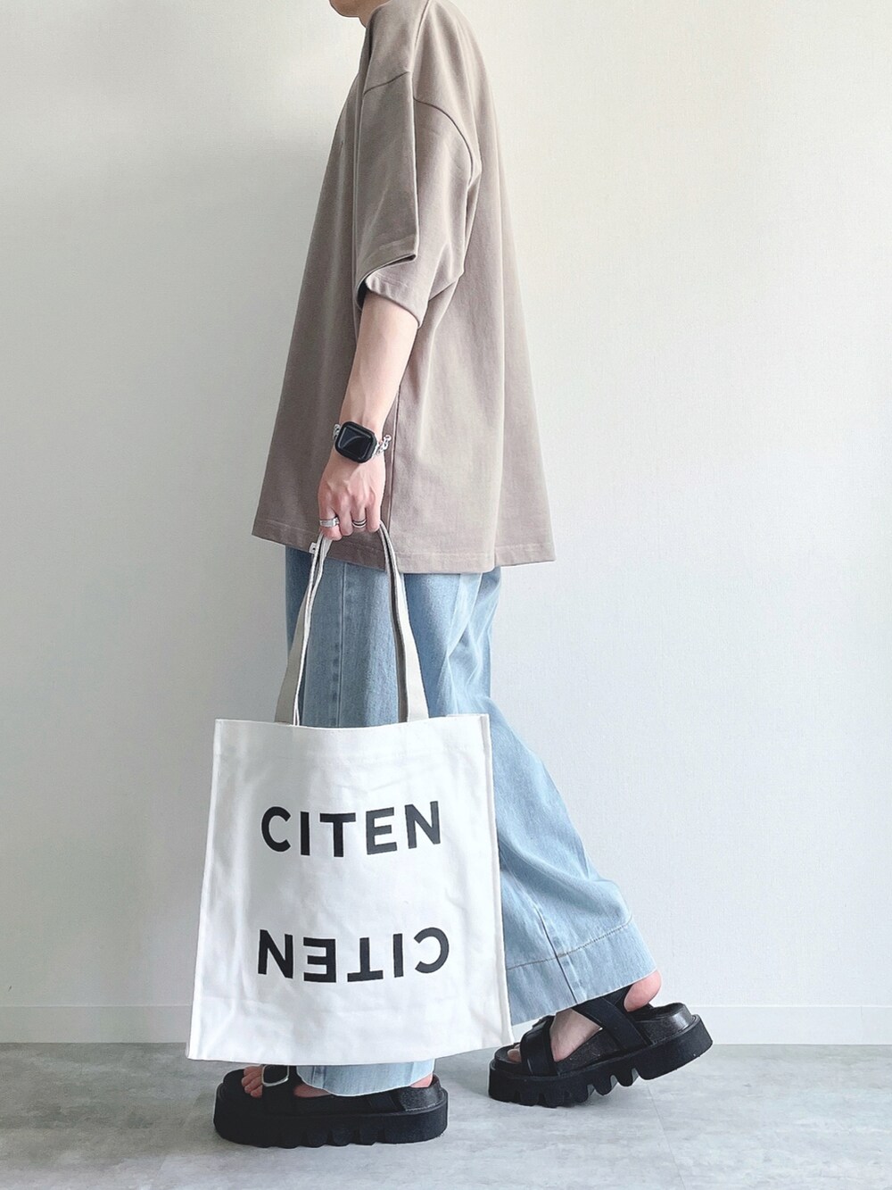 ベージュ系のTシャツ/カットソー、ブルー系のデニムパンツ、ブラック系のサンダルを着用したメンズの夏コーディネートの3枚目の写真