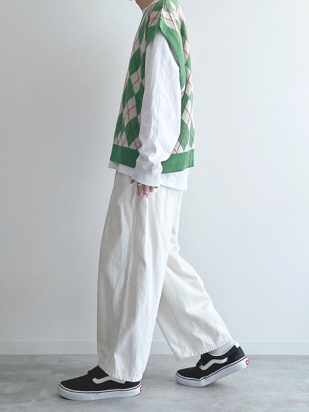 グリーン系のベスト、ホワイト系のTシャツ/カットソー、ベージュ系のパンツを着用したメンズの秋コーディネートの2枚目の写真