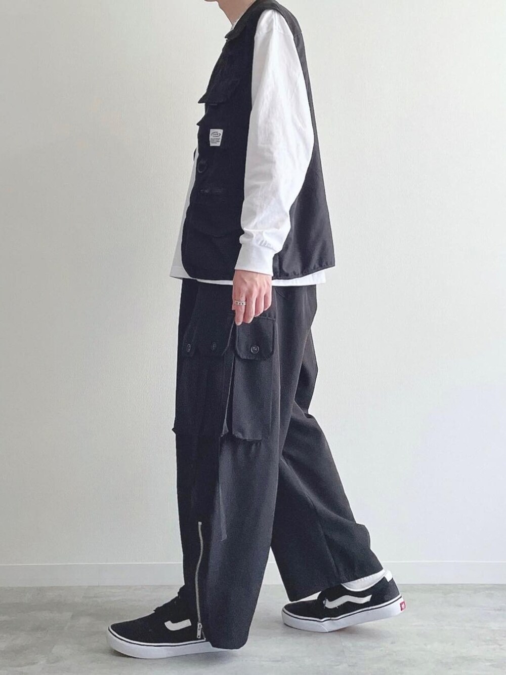 ブラック系のベスト、ホワイト系のTシャツ/カットソー、ブラック系のカーゴパンツを着用したメンズの秋コーディネートの2枚目の写真
