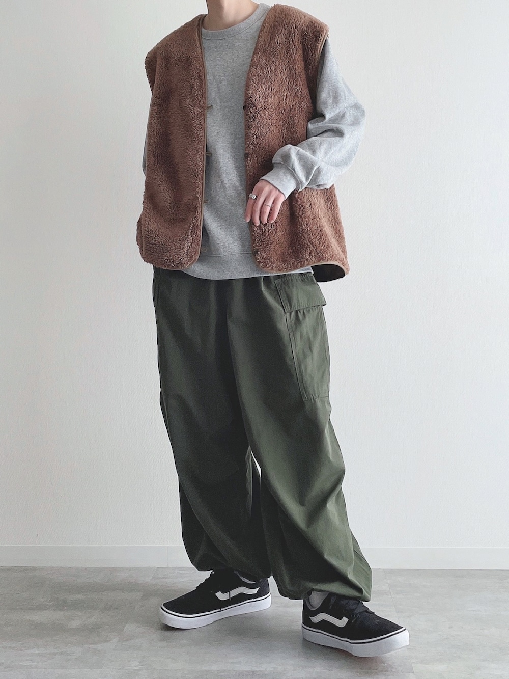 ブラウン系のベスト、グレー系のトップス、グリーン系のカーゴパンツを着用したメンズの秋コーディネートの2枚目の写真