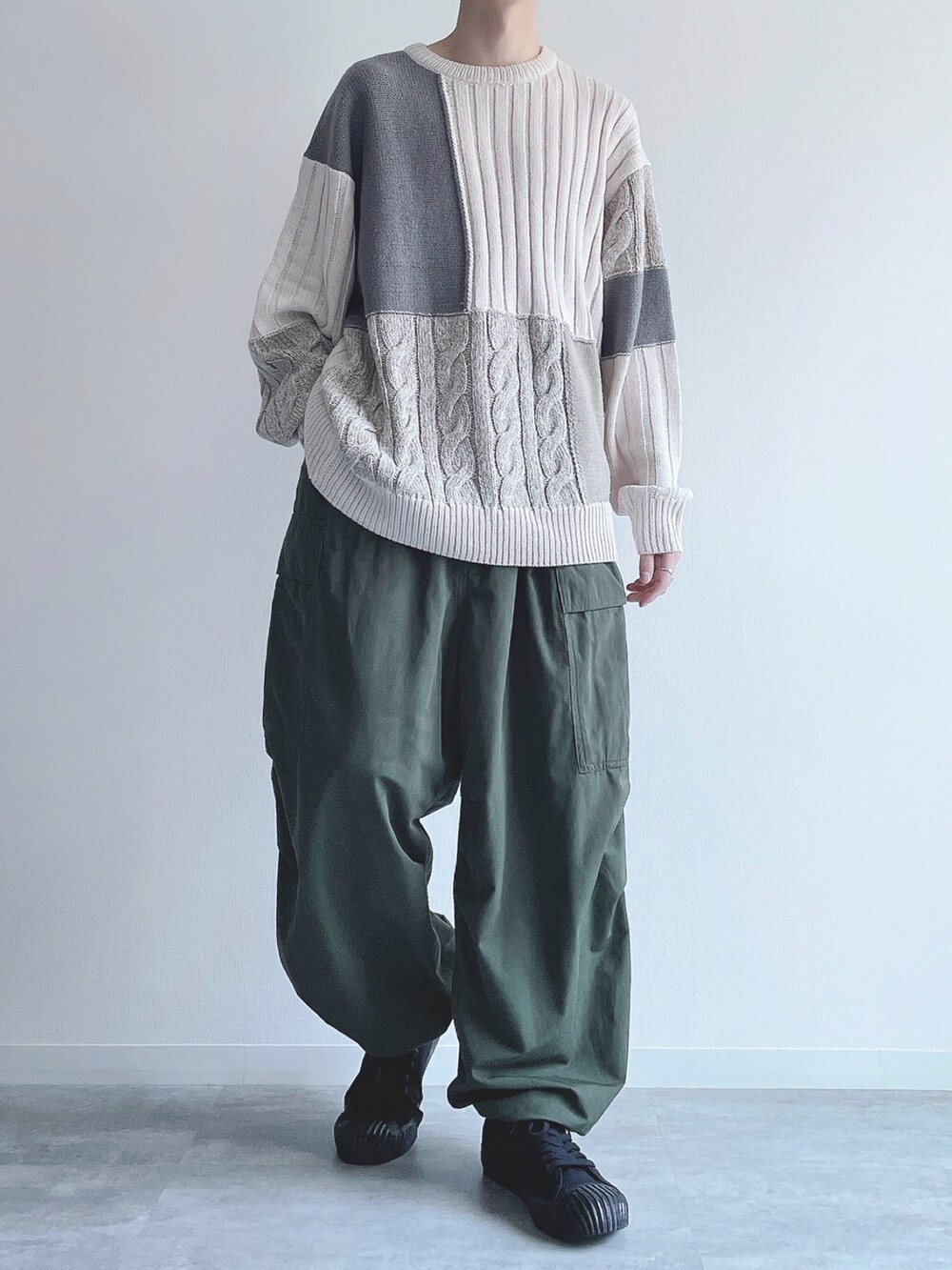 ホワイト系のニット/セーター、グリーン系のカーゴパンツ、ブラック系のスニーカーを着用したメンズの冬コーディネートの2枚目の写真