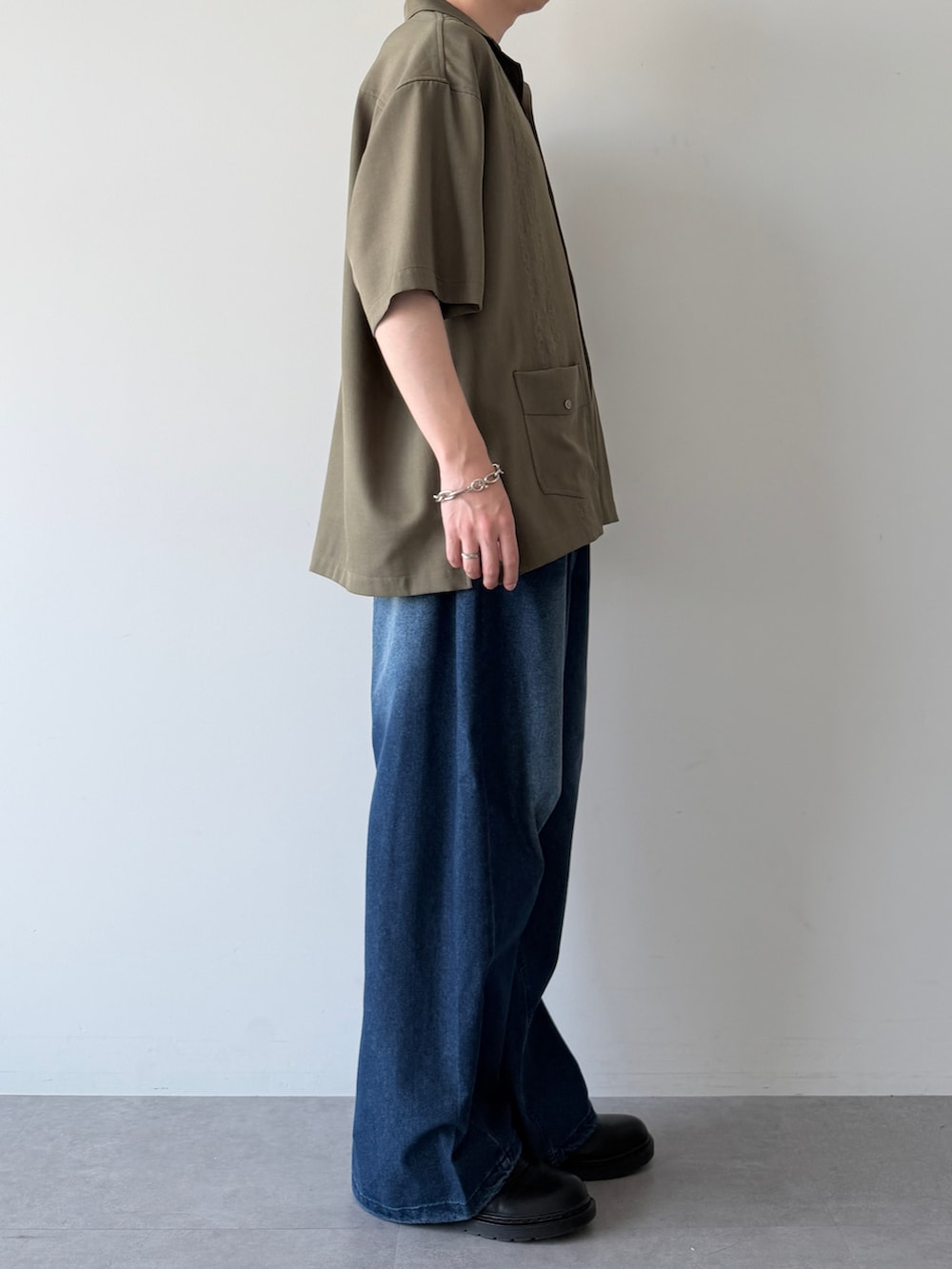 グリーン系のシャツ/ブラウス、ブルー系のデニムパンツ、ブラック系のシューズを着用したメンズの春コーディネートの3枚目の写真