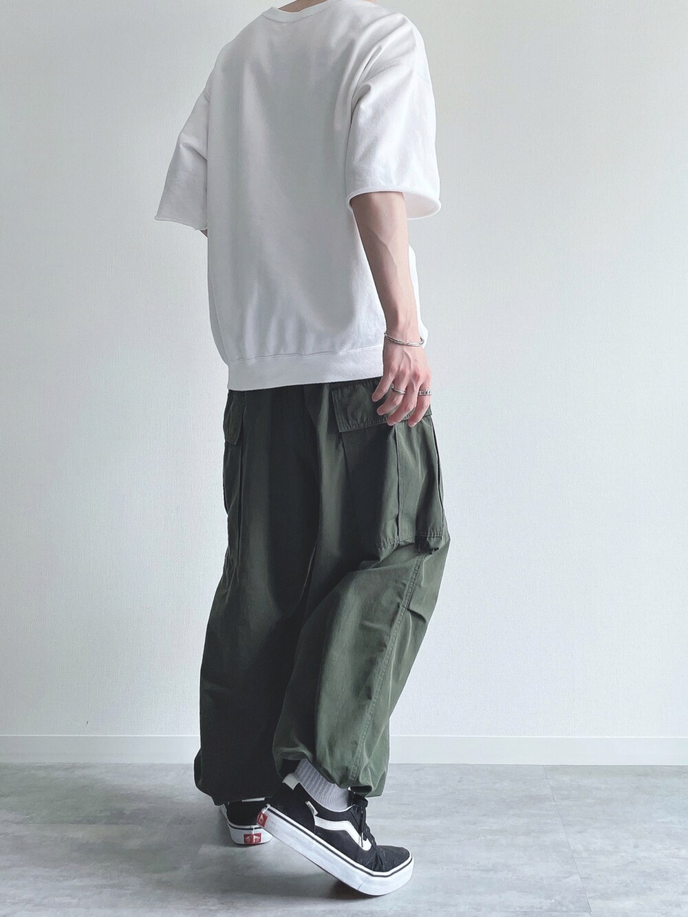 ホワイト系のTシャツ/カットソー、グリーン系のカーゴパンツ、ブラック系のスニーカーを着用したメンズの夏コーディネートの4枚目の写真