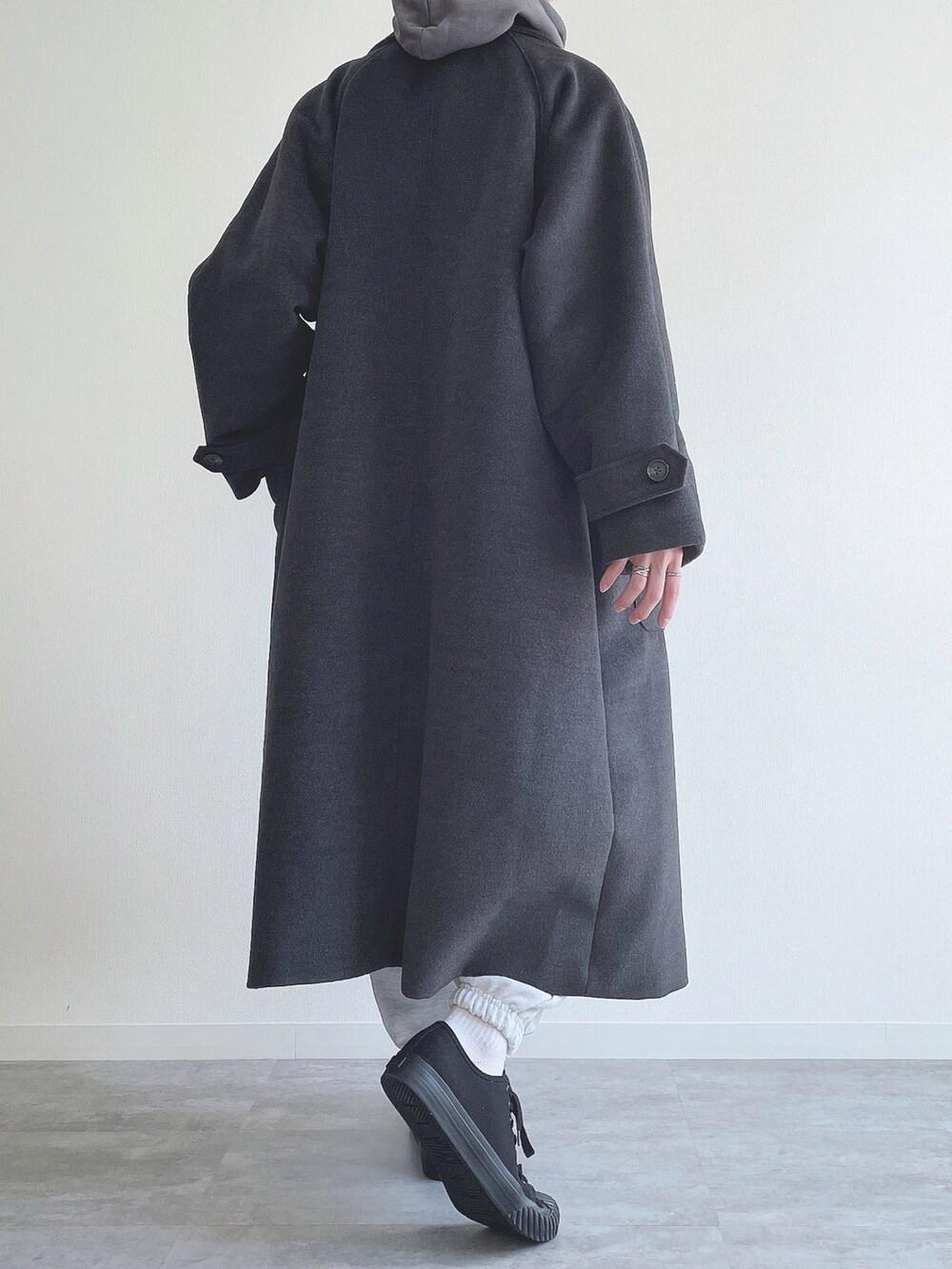 グレー系のステンカラーコート、ブルー系のTシャツ/カットソー、グレー系のスウェットパンツを着用したメンズの冬コーディネートの3枚目の写真