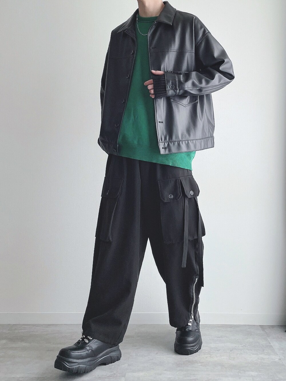 ブラック系のブルゾン、グリーン系のトップス、ブラック系のカーゴパンツを着用したメンズの秋コーディネートの2枚目の写真