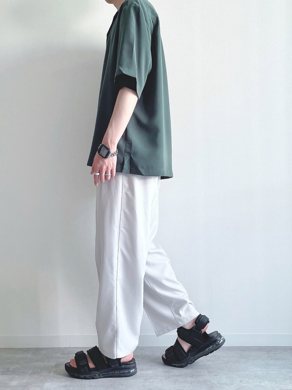 グリーン系のトップス、ブラック系のTシャツ/カットソー、ホワイト系のスラックスを着用したメンズの夏コーディネートの3枚目の写真