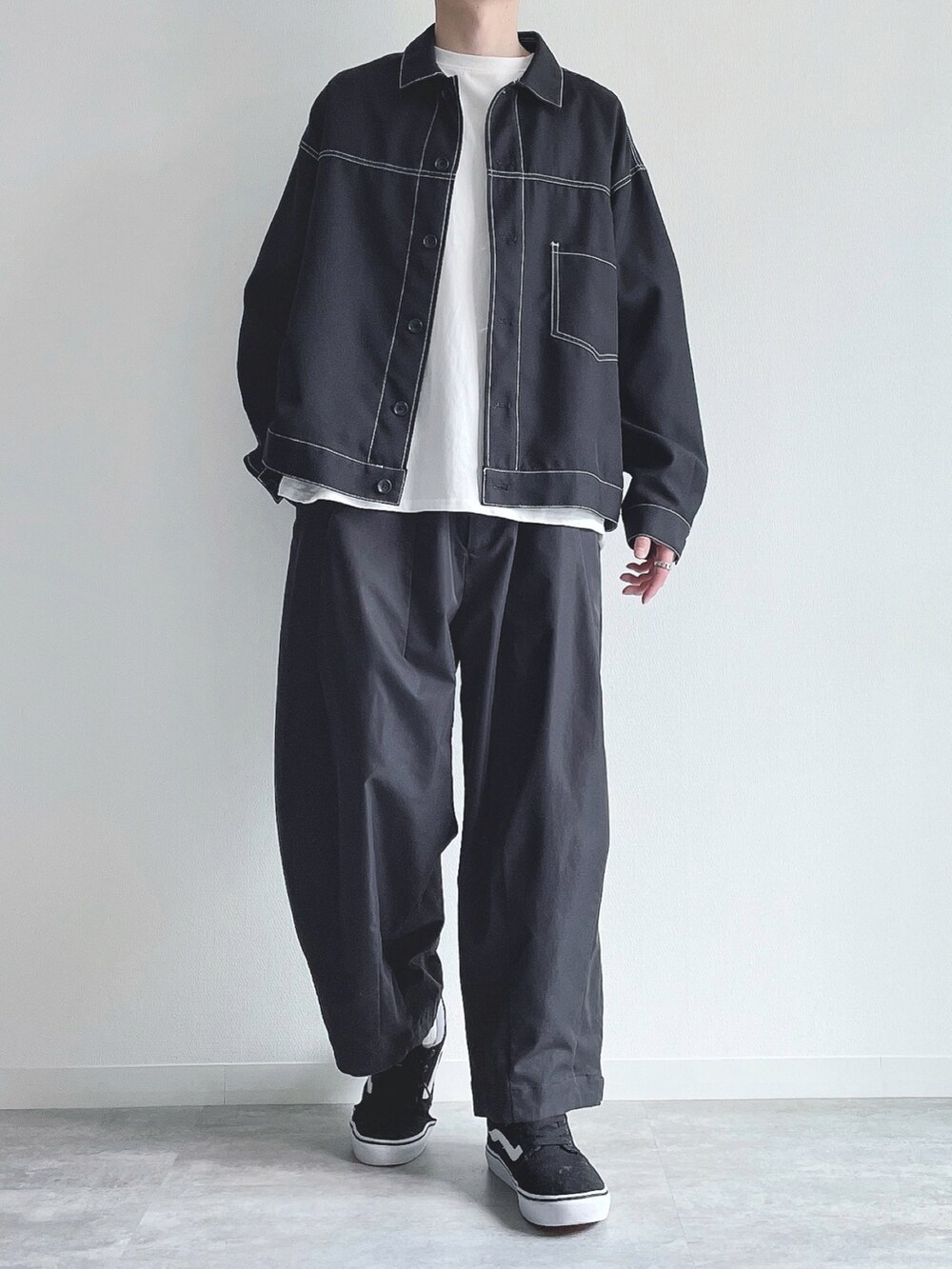 ブラック系のブルゾン、ホワイト系のTシャツ/カットソー、ブラック系のパンツを着用したメンズの春コーディネートの2枚目の写真