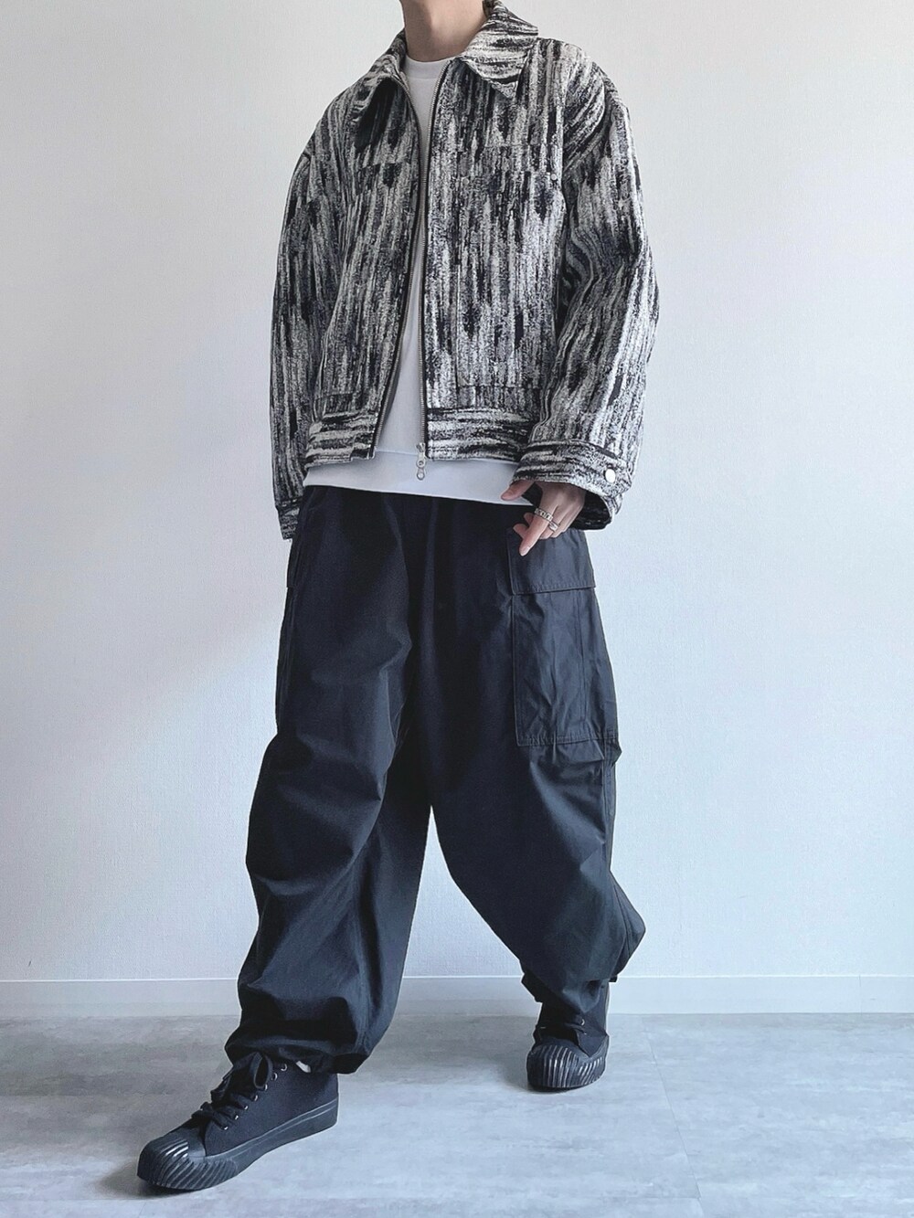 ホワイト系のブルゾン、ホワイト系のトップス、ブラック系のカーゴパンツを着用したメンズの冬コーディネートの5枚目の写真