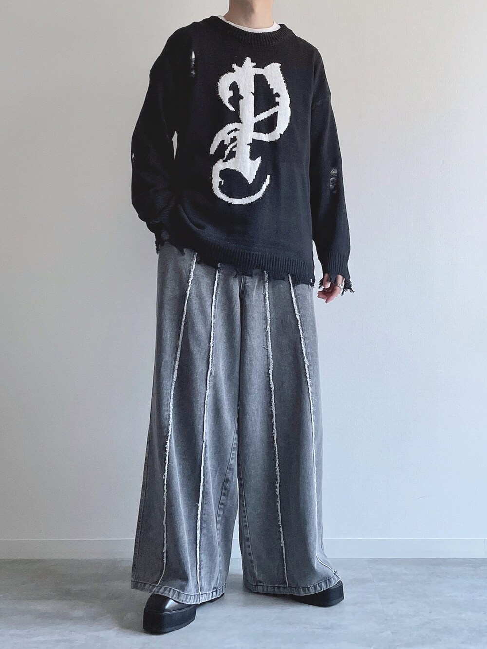 ブラック系のニット/セーター、ホワイト系のTシャツ/カットソー、グレー系のデニムパンツを着用したメンズの冬コーディネートの2枚目の写真