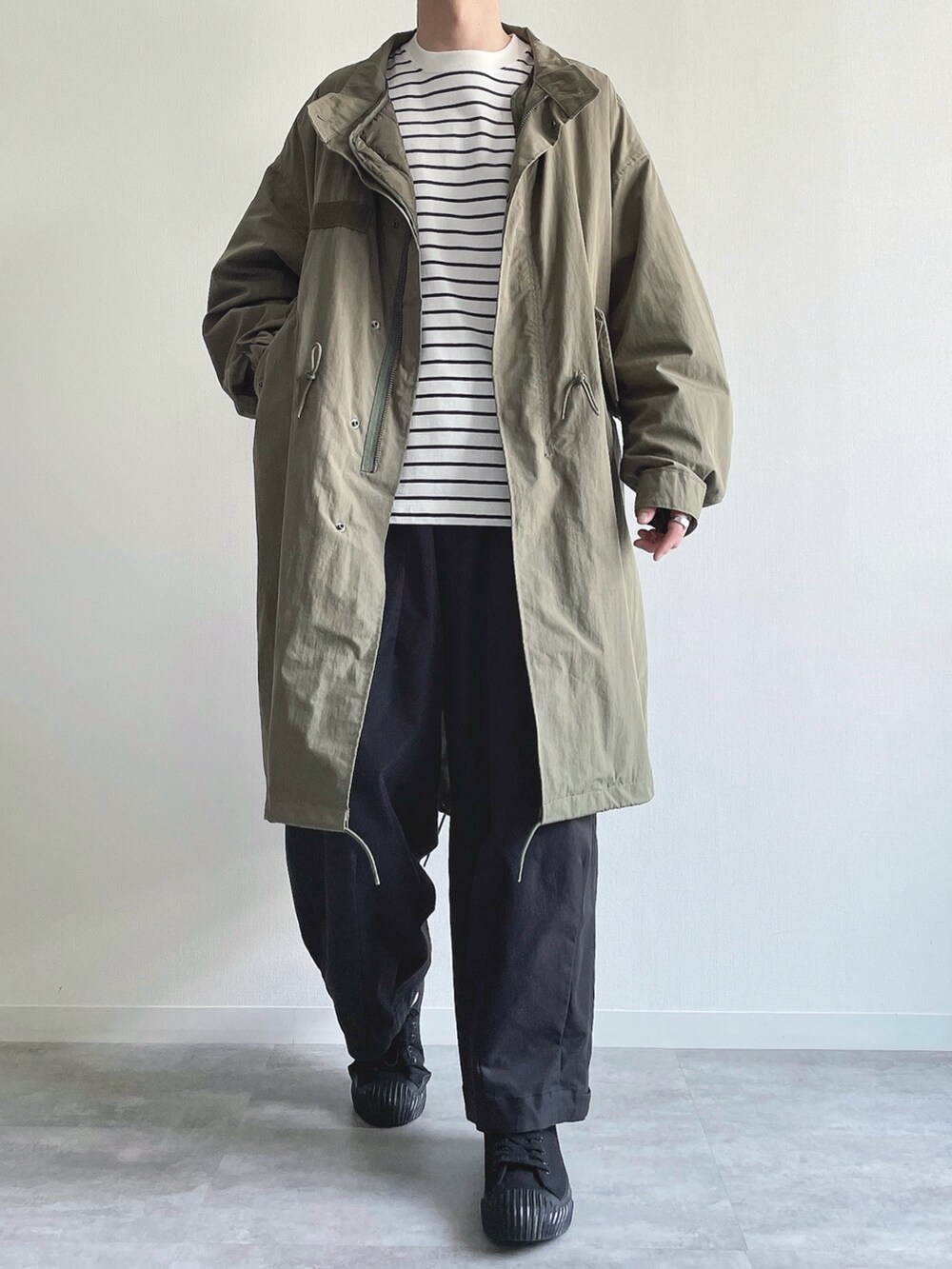 グリーン系のモッズコート、ホワイト系のTシャツ/カットソー、ブラック系のカーゴパンツを着用したメンズの春コーディネートの2枚目の写真