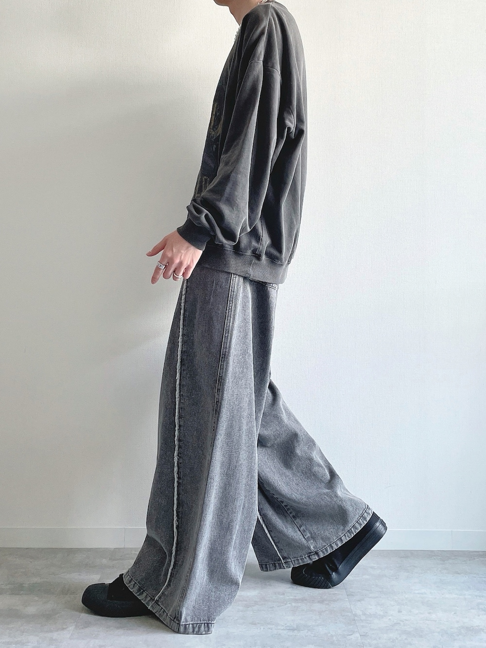 グレー系のスウェット、グレー系のデニムパンツ、ブラック系のスニーカーを着用したメンズの春コーディネートの3枚目の写真