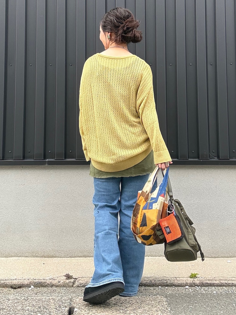 イエロー系のニット/セーター、ブラウン系のショルダーバッグ、オレンジ系のショルダーバッグを着用したレディースの夏コーディネートの3枚目の写真