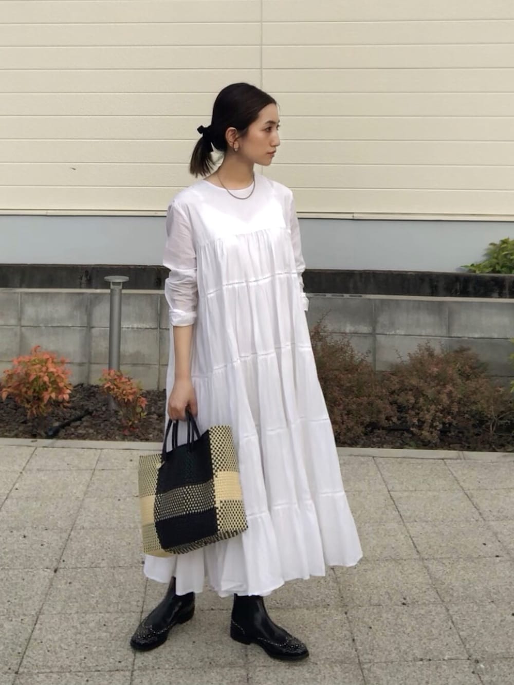 ホワイト系のワンピース、ブラック系のブーツ、ブラック系のかごバッグを着用したレディースの夏コーディネートの4枚目の写真