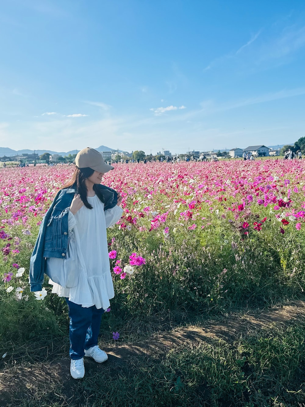 ブルー系のデニムジャケット、ブルー系のデニムパンツ、ホワイト系のスニーカーを着用したレディースの秋コーディネートの2枚目の写真