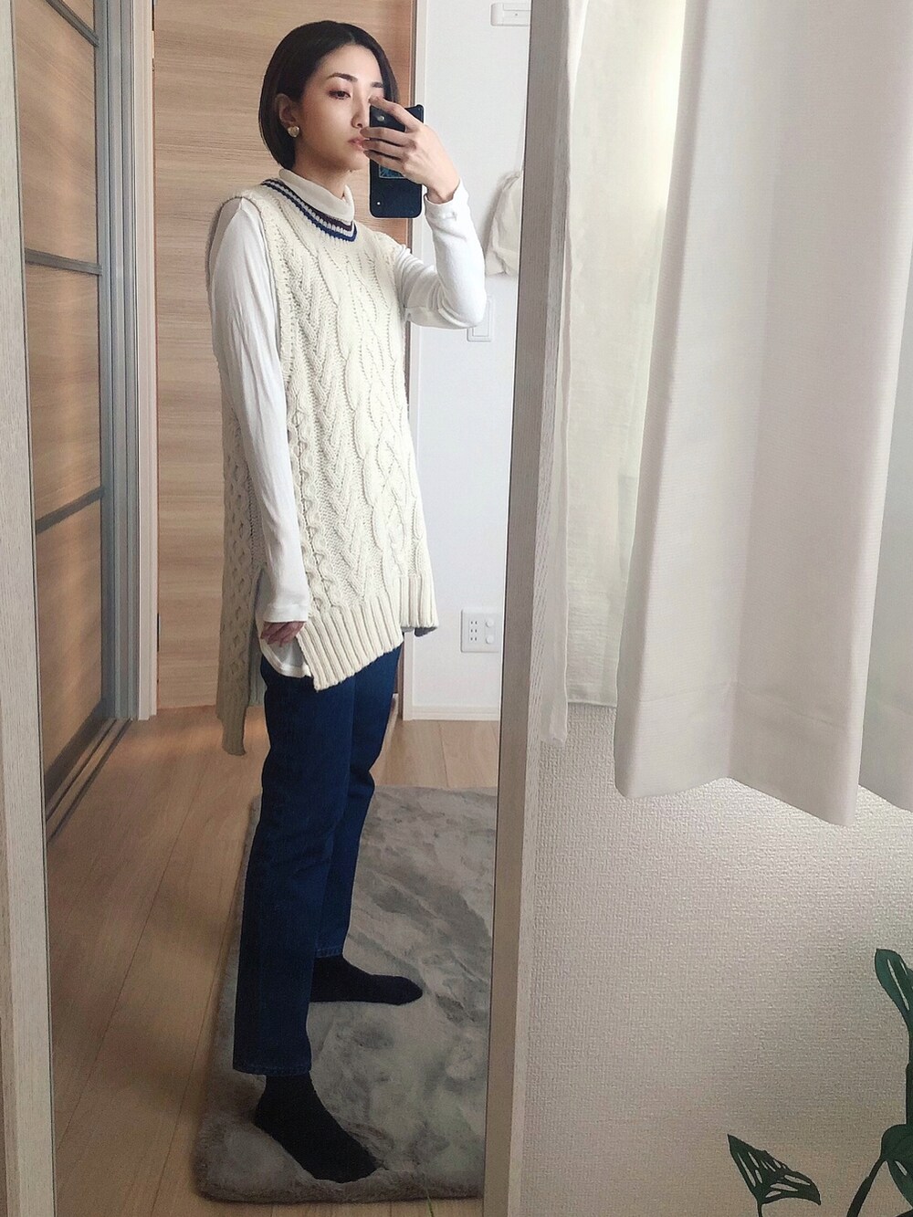 ブルー系のデニムパンツ、ホワイト系のニット/セーター、ホワイト系のトップスを着用したレディースの秋コーディネートの2枚目の写真