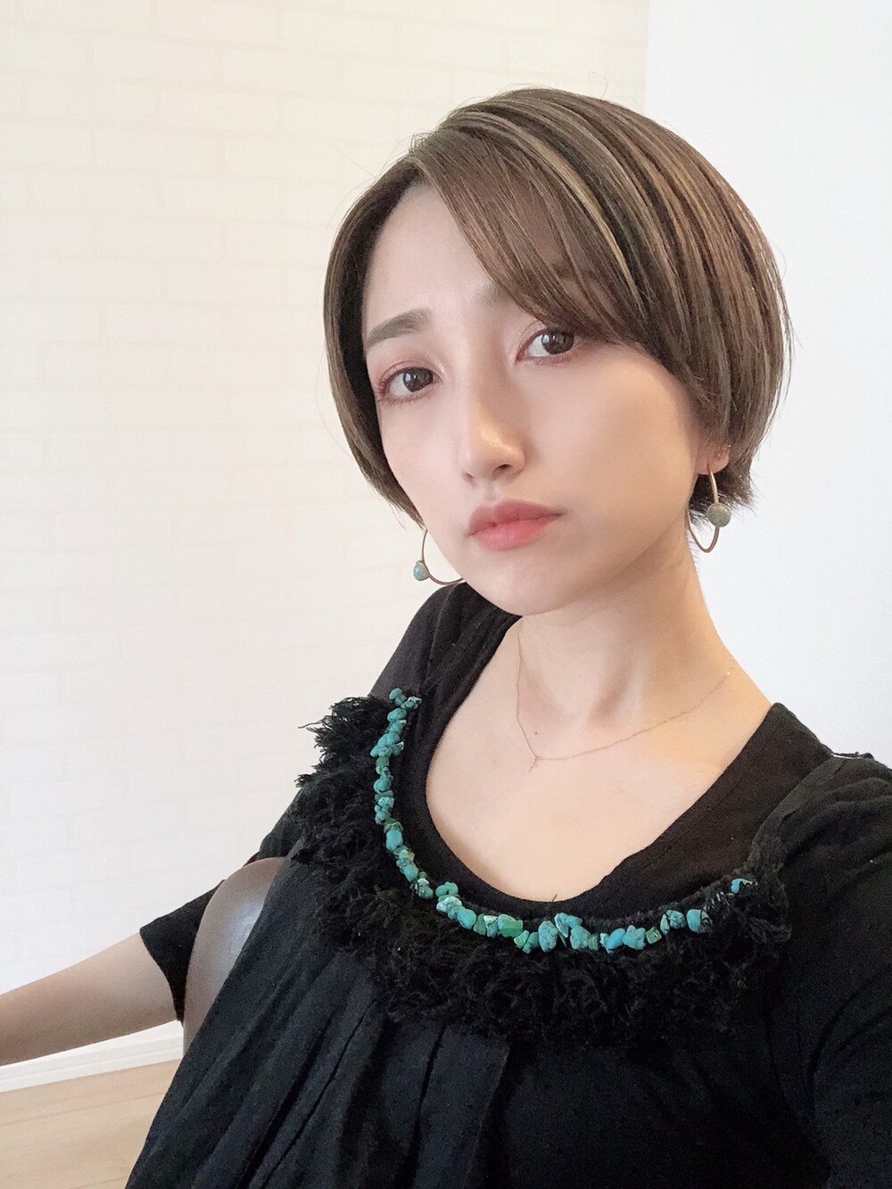 ブラック系のワンピース、ゴールド系のピアス（両耳用）を着用したレディースの春コーディネートの2枚目の写真