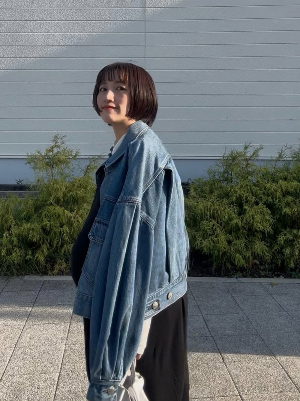 グレー系のモカシン/デッキシューズ、ブルー系のデニムジャケット、ブラック系のワンピースを着用したレディースの秋コーディネートの2枚目の写真