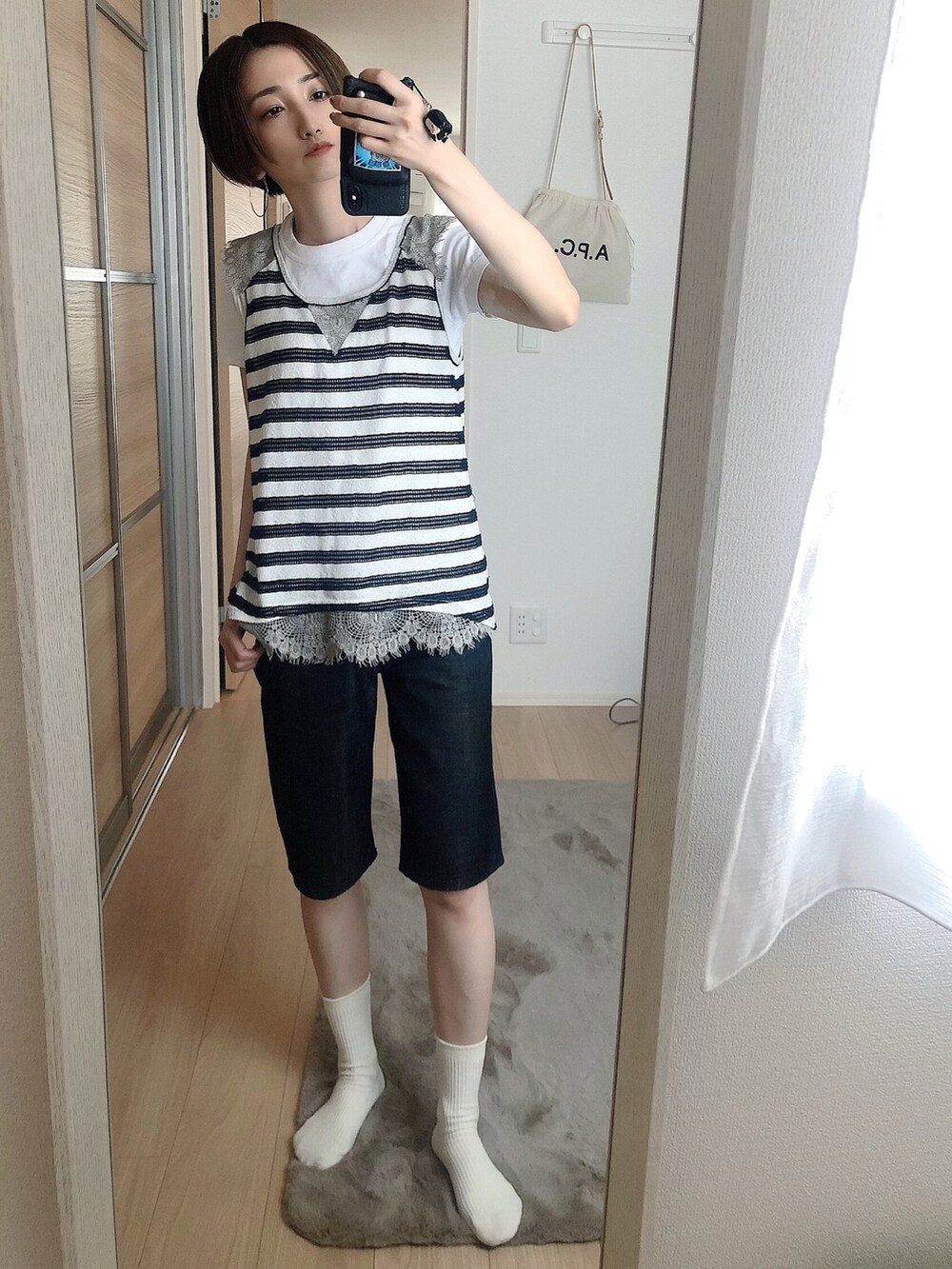 ブラック系のタンクトップ、ホワイト系のTシャツ/カットソー、ブラック系のデニムパンツを着用したレディースの夏コーディネートの2枚目の写真