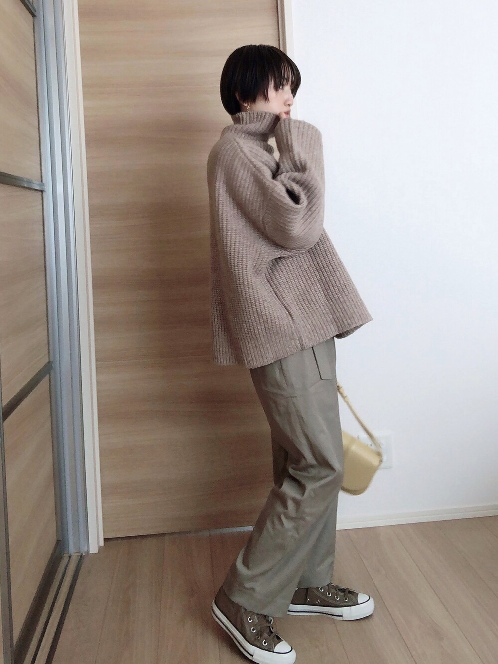 ベージュ系のトレンチコート、イエロー系のショルダーバッグ、ベージュ系のニット/セーターを着用したレディースの冬コーディネートの2枚目の写真