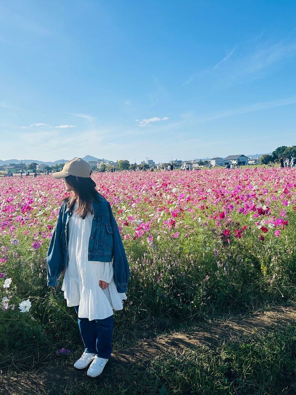 ブルー系のデニムジャケット、ブルー系のデニムパンツ、ホワイト系のスニーカーを着用したレディースの秋コーディネートの3枚目の写真