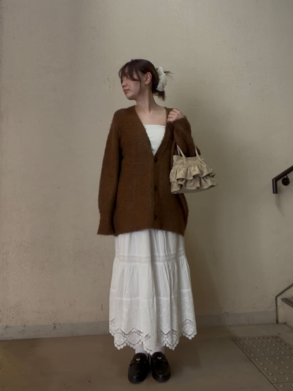 ブラウン系のカーディガン/ボレロ、ホワイト系のスカート、ベージュ系のハンドバッグを着用したレディースの秋コーディネートの3枚目の写真