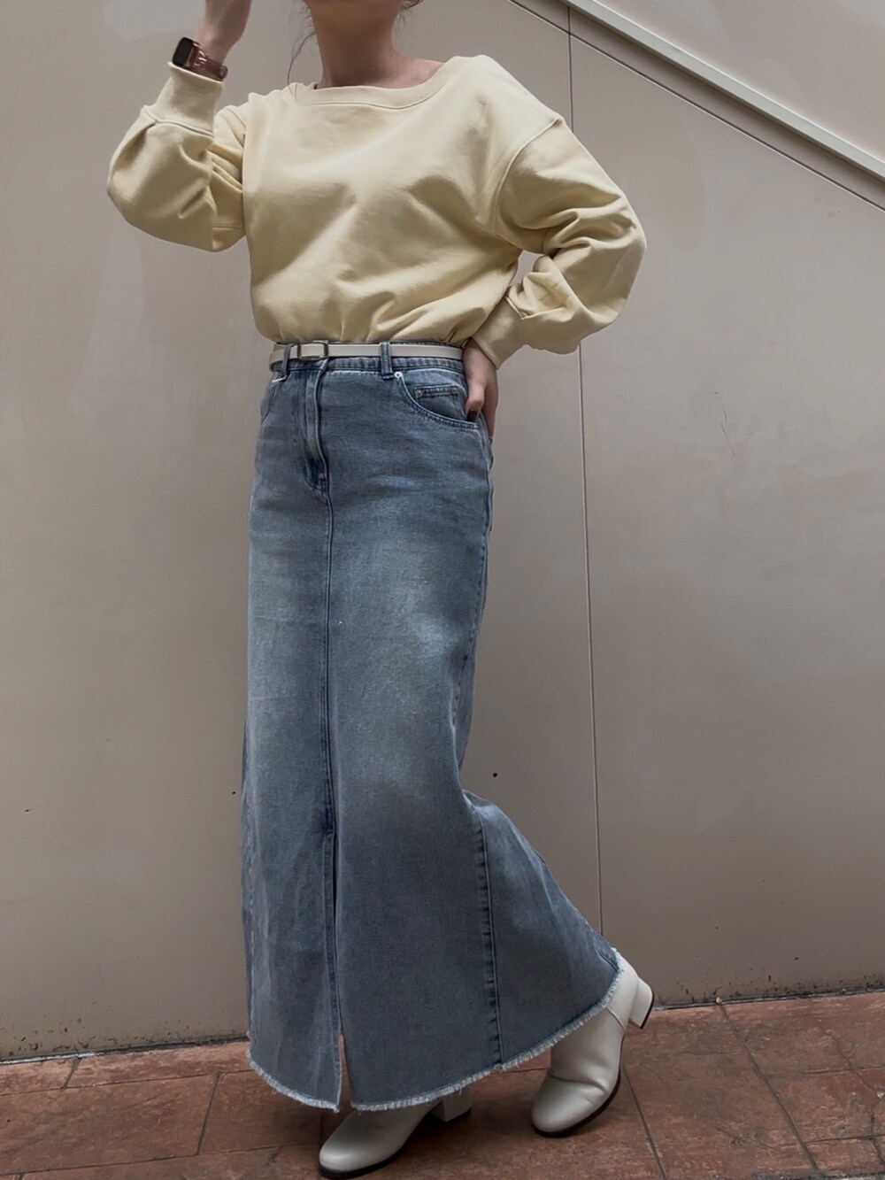 ブルー系のスカート、イエロー系のスウェット、ホワイト系のブーツを着用したレディースの冬コーディネートの2枚目の写真