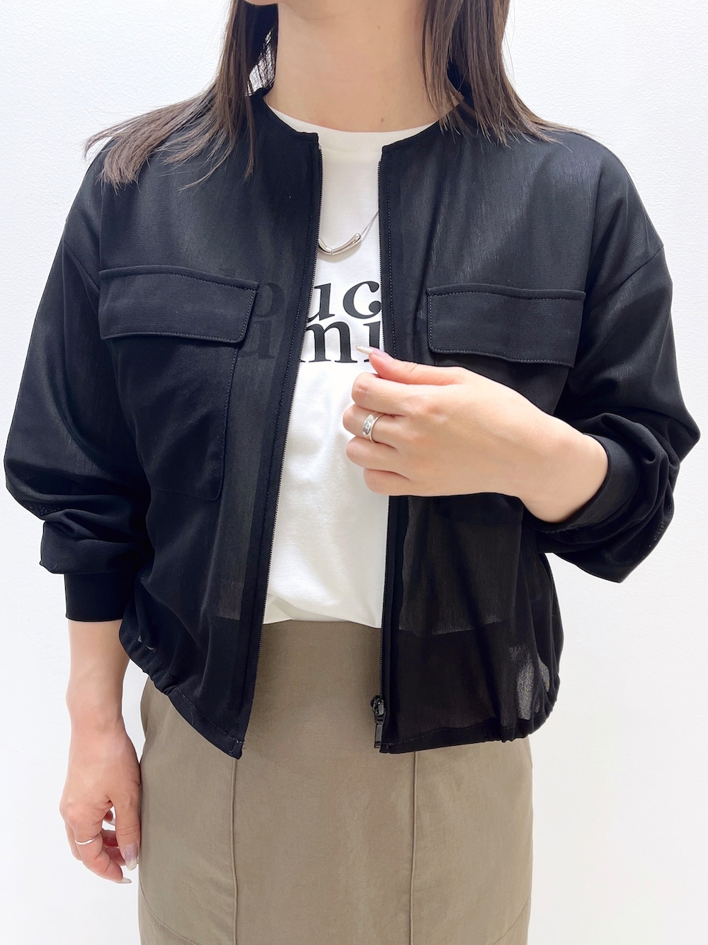 ブラック系のブルゾン、ホワイト系のTシャツ/カットソー、グリーン系のスカートを着用したレディースの春コーディネートの2枚目の写真