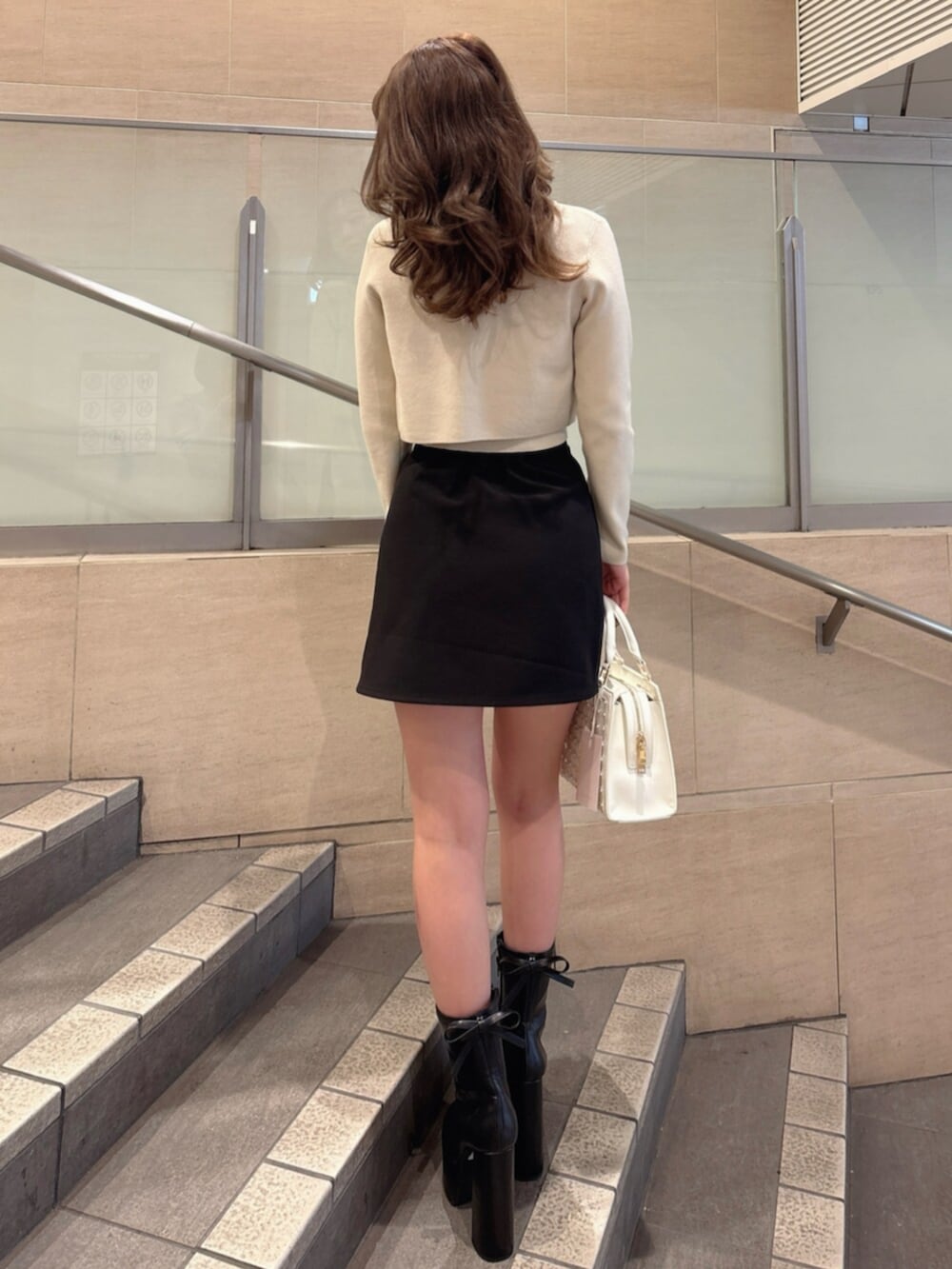 ブラック系のブーツ、ブラック系のスカート、ベージュ系のニット/セーターを着用したレディースの春コーディネートの4枚目の写真