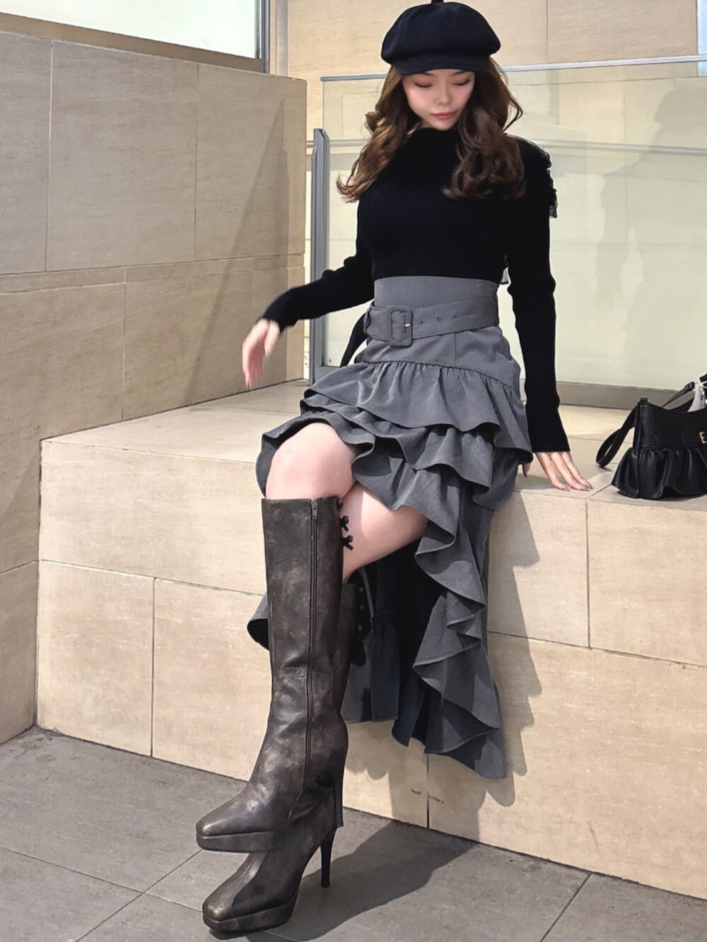 ブラック系のハンドバッグ、ブラック系のニット/セーター、グレー系のスカートを着用したレディースの春コーディネートの4枚目の写真