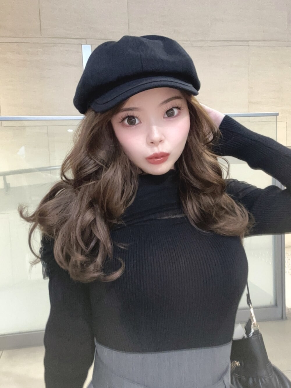 ブラック系のハンドバッグ、ブラック系のニット/セーター、グレー系のスカートを着用したレディースの春コーディネートの5枚目の写真